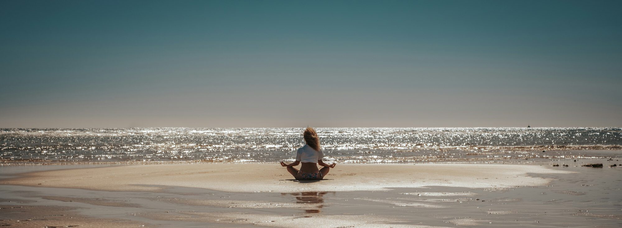 Inner balance life concept with woman sitting at the beach doing yoga meditation relax position